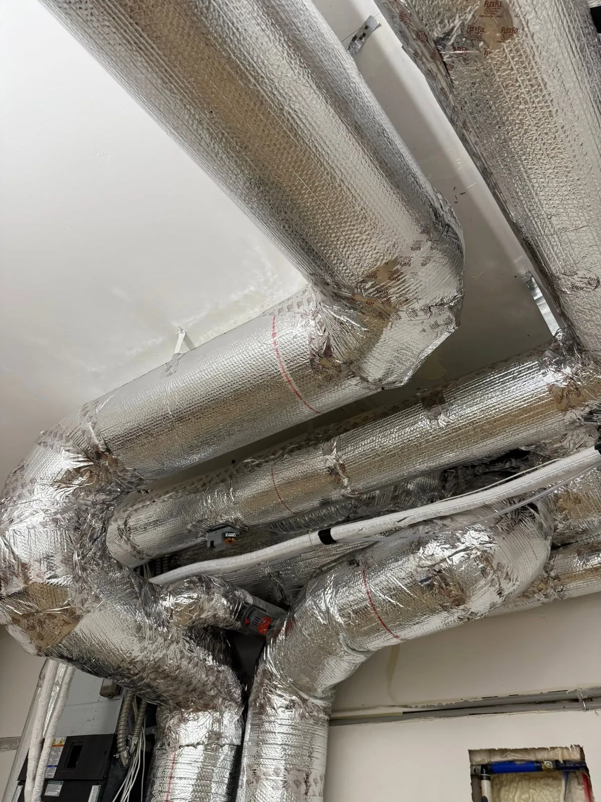 Insulated silver ducts meeting at a junction overhead